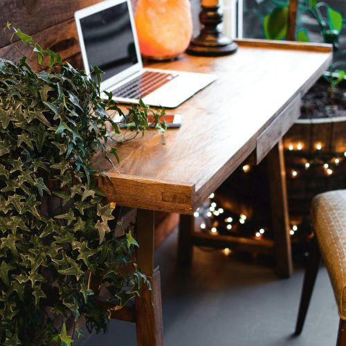 A cozy home office setup featuring a laptop, salt lamp, and plants on a wooden desk. Ideal for remote work.